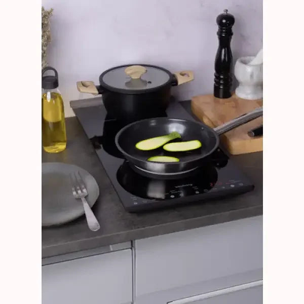 Piastra induzione Innoliving nera con pentola e padella che cucina verdure in cucina moderna