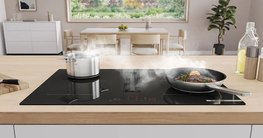 Piano cottura BOSCH a induzione moderno con pentola e padella che producono vapore in cucina luminosa