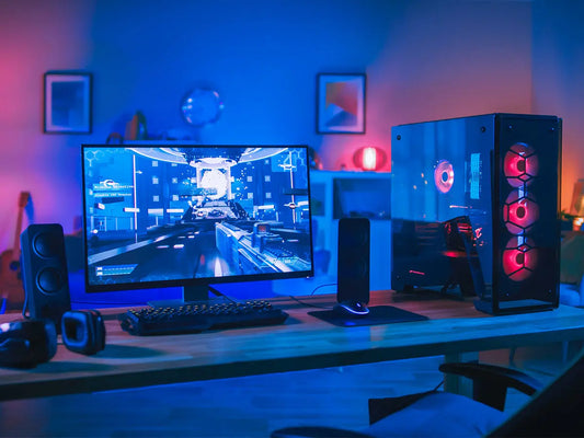 Postazione gaming con PC desktop illuminato e monitor con gioco, guida su come scegliere il computer giusto