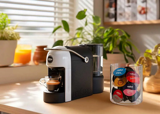 Macchina da caffè Lavazza con tazzina di espresso e assortimento di cialde di caffè colorate su tavolo